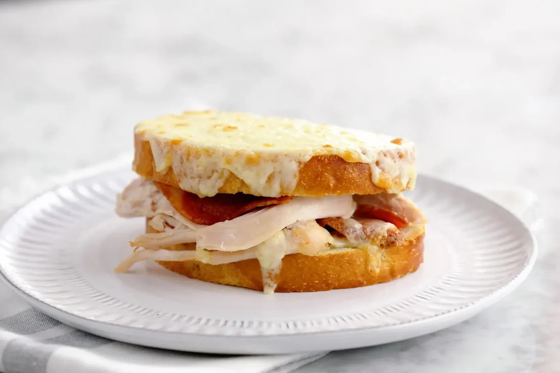 Turkey grilled cheese sandwich served in a white tray.