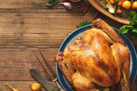 Thanksgiving dinner spread with turkey, vegetables, and assorted food on a rustic wooden table.