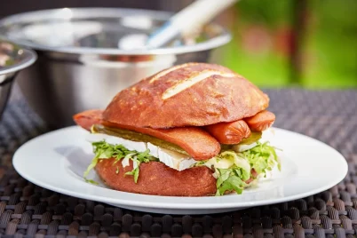 Butr Grilledturkeyfrankspretzelbun BLT turkey burger served in a white tray.