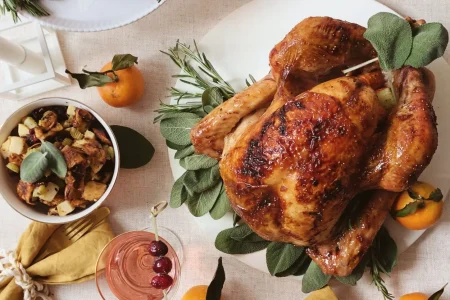 Thanksgiving dinner table decorated with whole turkey, pie, donuts and green beans.