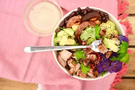 Chili lime burrito bowl placed on wooden tray with a side of dip.