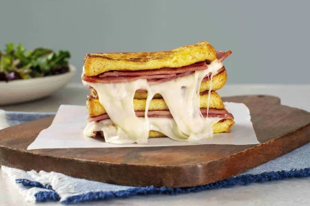 Monte Cristo sandwich with turkey bacon placed on a wooden tray
