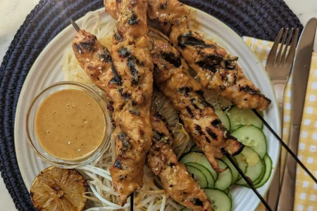 Grilled turkey skewers with cucumbers, lemon and dip placed on a plate