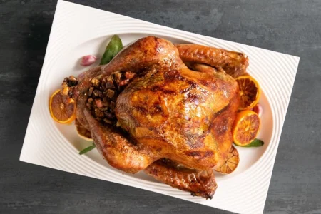 278217509_3132855480286310_1303861030055811564_n Roasted whole turkey decorated with lemon placed on a white tray.