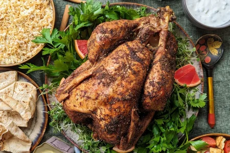 PXL_20230826_1813396363-1-scaled A middle eastern spiced whole turkey placed in the middle of the table with bread, rice and spices on the side.